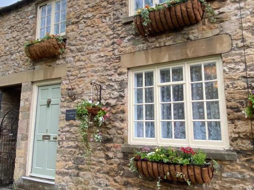 a stone house with windows and flowerpots on it at Borough Beck Cottage in Helmsley