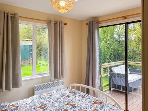 a bedroom with a bed and a balcony with windows at Drumble Lodge in Astbury