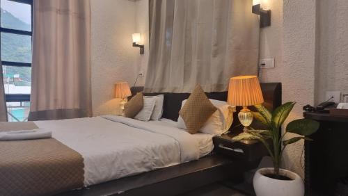a bedroom with a bed with two lamps and a plant at Oslo Ganges by Around stays, Tapovan in Rishīkesh