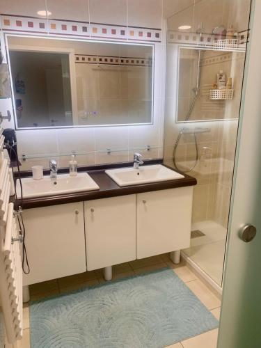 une salle de bain avec deux lavabos et une douche dans l'établissement Grand appartement les pieds dans l'eau, à La Baule