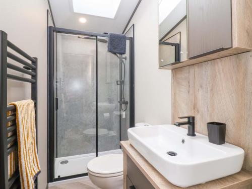 une salle de bain avec un lavabo blanc et une douche dans l'établissement Hazelnut Lodge, à Chipping Norton