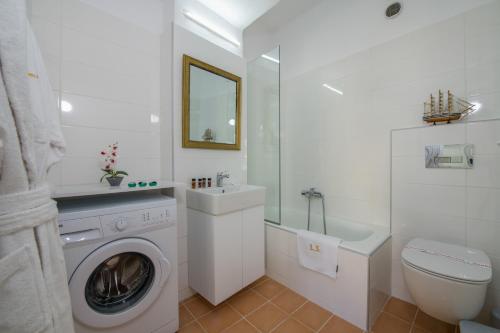 a white bathroom with a washing machine and a sink at Lucky Suites in Rethymno Town