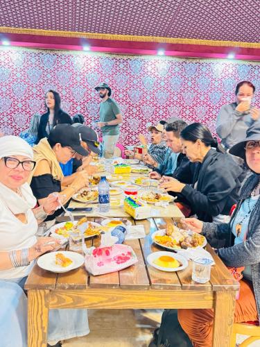 a group of people sitting around a table eating food at Wadi Rum Legend Luxury Camp in Wadi Rum