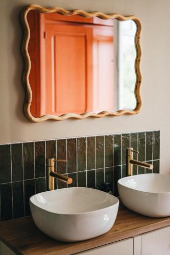 une salle de bain avec deux lavabos et un miroir dans l'établissement La Maison Léon, à Biscarrosse