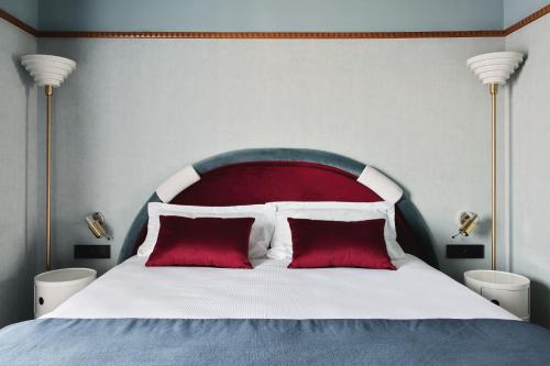 a bed with a red headboard and two red pillows at Hôtel Mercedes in Paris
