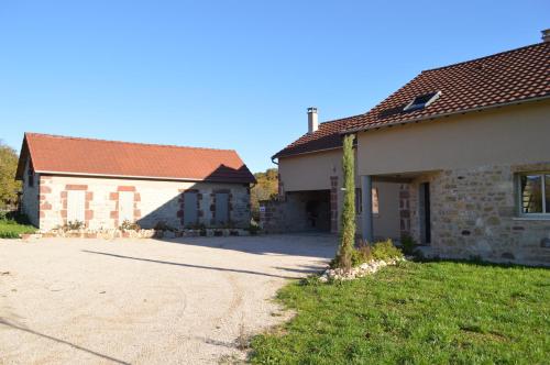 un vieux bâtiment en briques avec un arbre devant lui dans l'établissement La maison du Romarin, à Meyssac