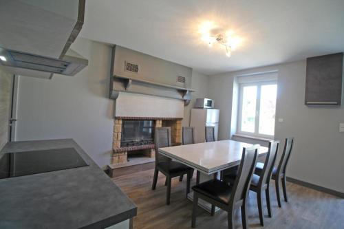 a kitchen and dining room with a table and a fireplace at Le paradis de caux in Magnac-Bourg