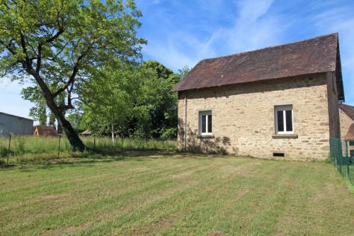 an old stone building with a grass field and a tree at Le paradis de caux in Magnac-Bourg