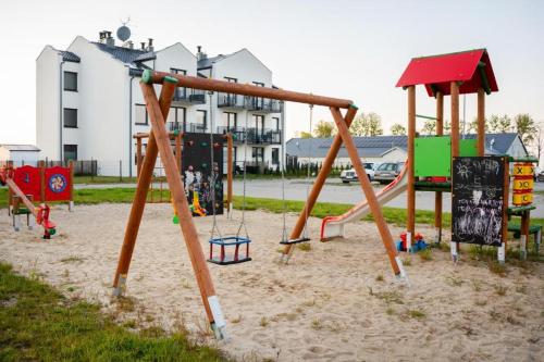 einen Spielplatz mit einer Schaukel im Sand in der Unterkunft Apartament Morelowa in Władysławowo