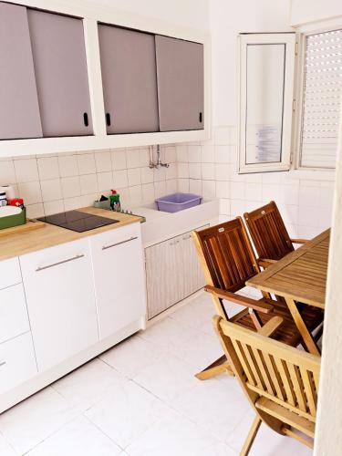 une cuisine avec des armoires blanches et une table et des chaises dans l'établissement L'anguille du port, à Port-la-Nouvelle