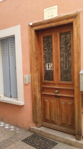una porta di legno sul lato di un edificio di Appartement cosy de 50m2, 2 chambres avec terrasse, plein centre d'Ax-les-Thermes ad Ax-les-Thermes
