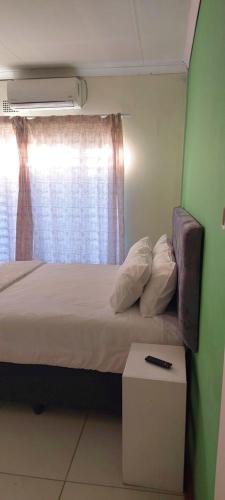 a small bedroom with a bed and a window at Elite Stay Guest House in Rustenburg