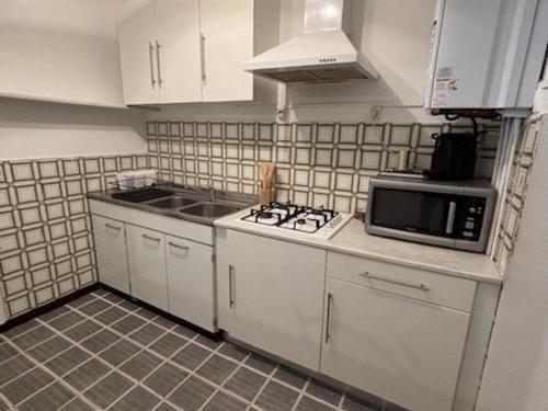 une cuisine avec une cuisinière et un micro-ondes dans l'établissement T2 La Grande Motte à 150m de la plage, 6 couchages, terrasse - FR-1-250-316, à La Grande Motte