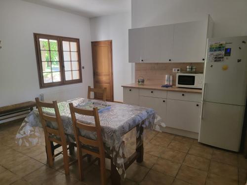 une cuisine avec une table avec des chaises et un réfrigérateur dans l'établissement maison de campagne, à Le Vernet