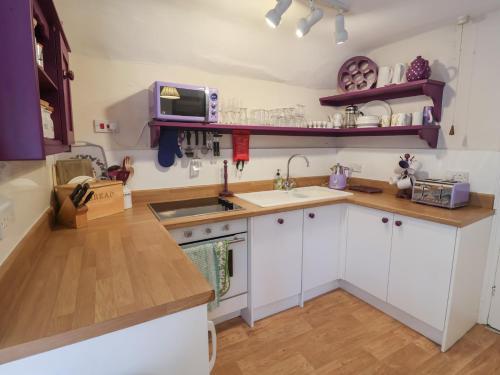 a kitchen with white cabinets and a sink and a microwave at The Plover in Holt