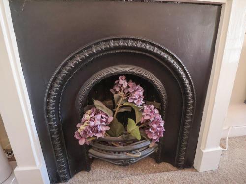 a black fireplace with purple flowers in a vase at The Plover in Holt