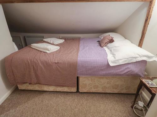 a bed in a small room with two pillows on it at The Plover in Holt