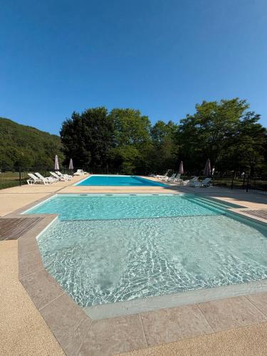 une piscine bleue avec des chaises et des arbres dans l'établissement Mobilhome Le Chene, à Saint-Pompont