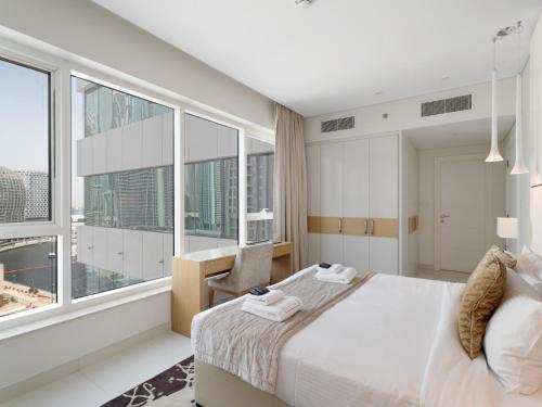 a bedroom with a large bed and large windows at Stylish 1BR at Damac Maison -Your Grand Canal Getaway in Dubai
