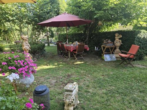 a garden with a table and chairs and an umbrella at Domaine du lagon bleu in Comps