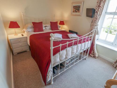 a bedroom with a bed with a red bedspread and a window at Pebble in Holt