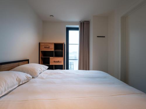 a bedroom with a large white bed and a window at Apartment Elyana with balcony by Interhome in Blankenberge