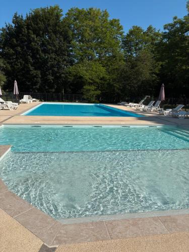 une piscine bleue avec des chaises et des arbres dans l'établissement Mobilhome Le Noyer, à Saint-Pompont