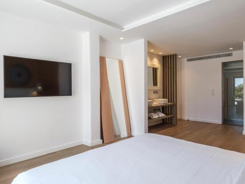 a bedroom with a bed and a television on a wall at Villa DM by Ethos Hospitality in Agios Ioannis Mykonos