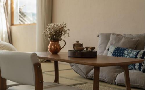 a coffee table in a living room with a vase of flowers at 沙溪坡上村花隐世民宿 in Diannan
