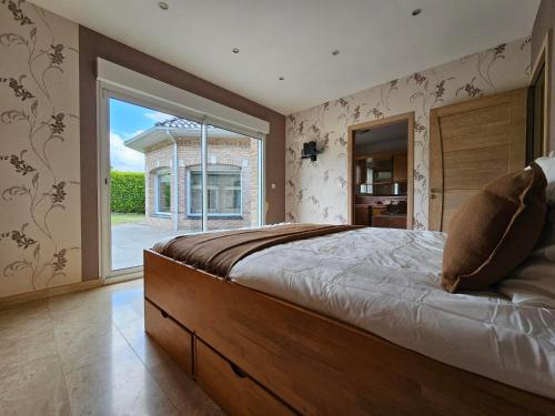 une chambre avec un grand lit et une grande fenêtre dans l'établissement Villa avec piscine privée interieure chauffée, à Monchy-Breton