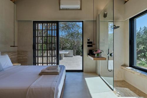 a bedroom with a bed and a glass shower at OPENNESS House by the sea in Marathi