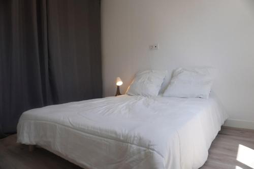 un lit avec des draps blancs et des oreillers dans une chambre dans l'établissement Le Dauphin du port, à Port-la-Nouvelle