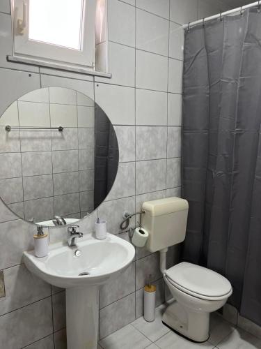 a bathroom with a sink and a toilet and a mirror at Apartment MJ in Čapljina