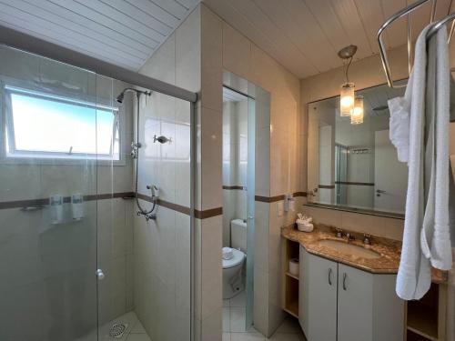 Un baño con ducha, lavabo e inodoro. en Bombinhas Blue Suítes, en Bombinhas