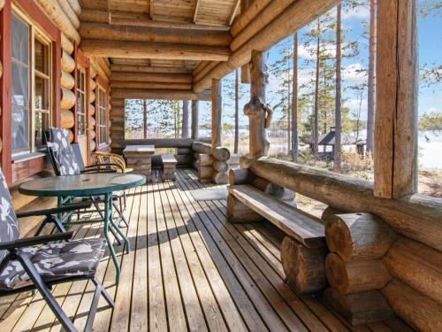 eine Veranda eines Blockhauses mit einem Tisch und Stühlen in der Unterkunft Holiday Home Metsäneuvos by Interhome in Eno