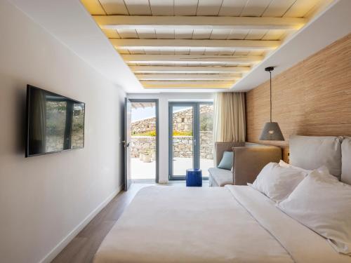 a bedroom with a bed and a tv and a couch at Villa DM by Ethos Hospitality in Agios Ioannis Mykonos