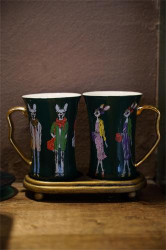 two green coffee mugs with cartoon people on them at 沙溪坡上村花隐世民宿 in Diannan