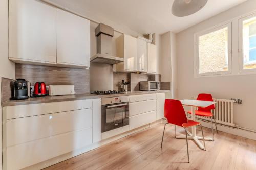 une cuisine avec des placards blancs, des chaises rouges et une table dans l'établissement Exceptionnel appartement avec vue Place de la Comédie, à Montpellier