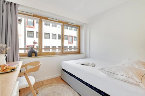 ein Schlafzimmer mit Bett, Schreibtisch und Fenster in der Unterkunft Résidence Arc de Triomphe avec Rooftop in Paris