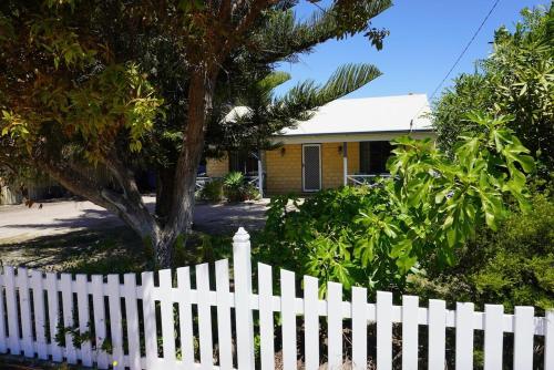 a white picket fence in front of a house at Kindlewood Cottage in Esperance