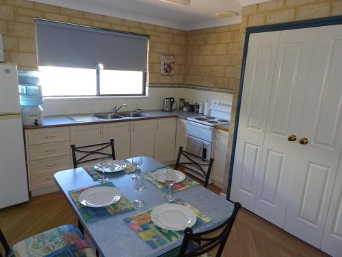 a kitchen with a table with plates and glasses on it at Kindlewood Cottage in Esperance