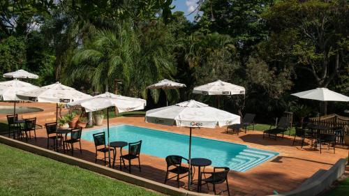 a swimming pool with tables and chairs and umbrellas at SR Farm Hotel in Brotas