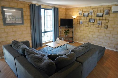 a living room with a couch and a table at Kindlewood Cottage in Esperance