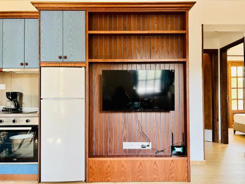 a kitchen with a tv in a wooden entertainment center at Elgi Cottage in Chrysi Ammoudia