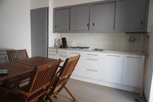 une cuisine avec des armoires blanches et une table et des chaises en bois dans l'établissement L'espadon du port, air conditioning, terrace, sea, 5 people, à Port-la-Nouvelle