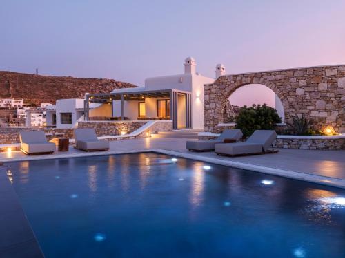 a villa with a swimming pool at night at Villa DM by Ethos Hospitality in Agios Ioannis Mykonos