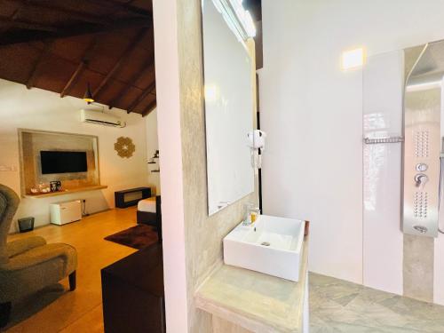 a bathroom with a sink and a living room at Rankendiya Resort - Habarana in Habarana