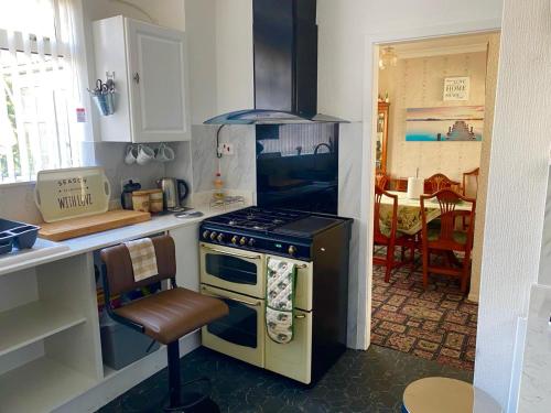 a kitchen with a stove and a chair in it at Northern homestay between High Peak & Manchester in Hadfield