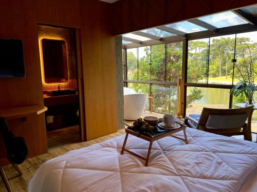 a bedroom with a bed with a table on it at WoodStone Hotel Fazenda in Gramado