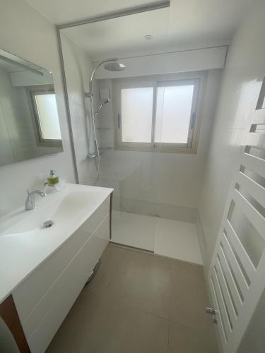 une salle de bain blanche avec un lavabo et un miroir dans l'établissement Apt Cannes Centre - Proche des Plages et du Palais des festivals - Climatisation - Parking privée, à Cannes